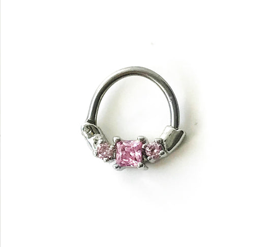 Hinged segment ring with 3 prong set pink cubic zirconia gems. 16 gauge X 8mm. This clicker is on the small side, for a snug fit. This segment ring is great for septum, daith, or other cartilage piercings. Bar is surgical steel, dangle material is plated brass.