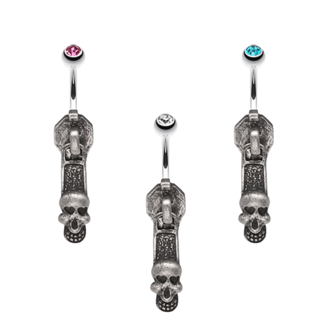 Three antique toned zipper pull belly button rings with skull charms and pink, clear, and blue top gemstones on a white background.