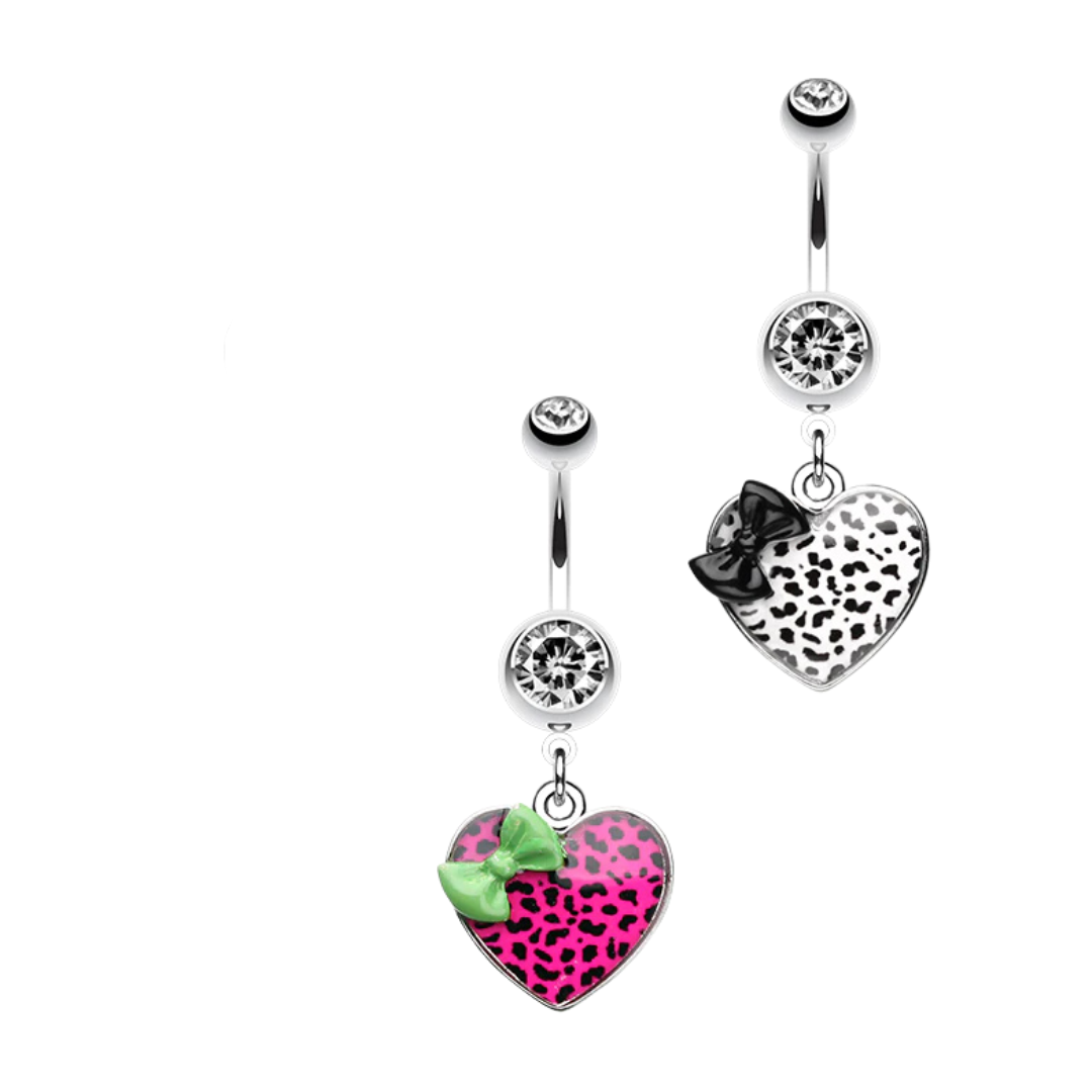Three surgical steel belly rings with heart-shaped dangling charms, each featuring a different leopard print design: purple and black, silver and black, and pink and black with a green bow accent.
