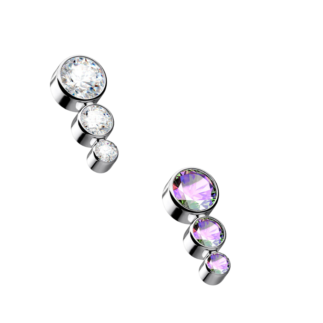 Two internally threaded titanium ascending cluster piercing tops on a white background, each featuring three bezel-set round crystals of decreasing sizes, with one top in clear white gems and the other in iridescent Aurora Borealis gems.