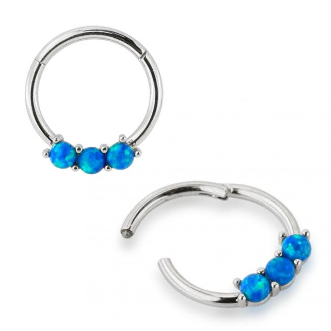 A stainless steel hinged segment ring with three blue opal gems on one side.