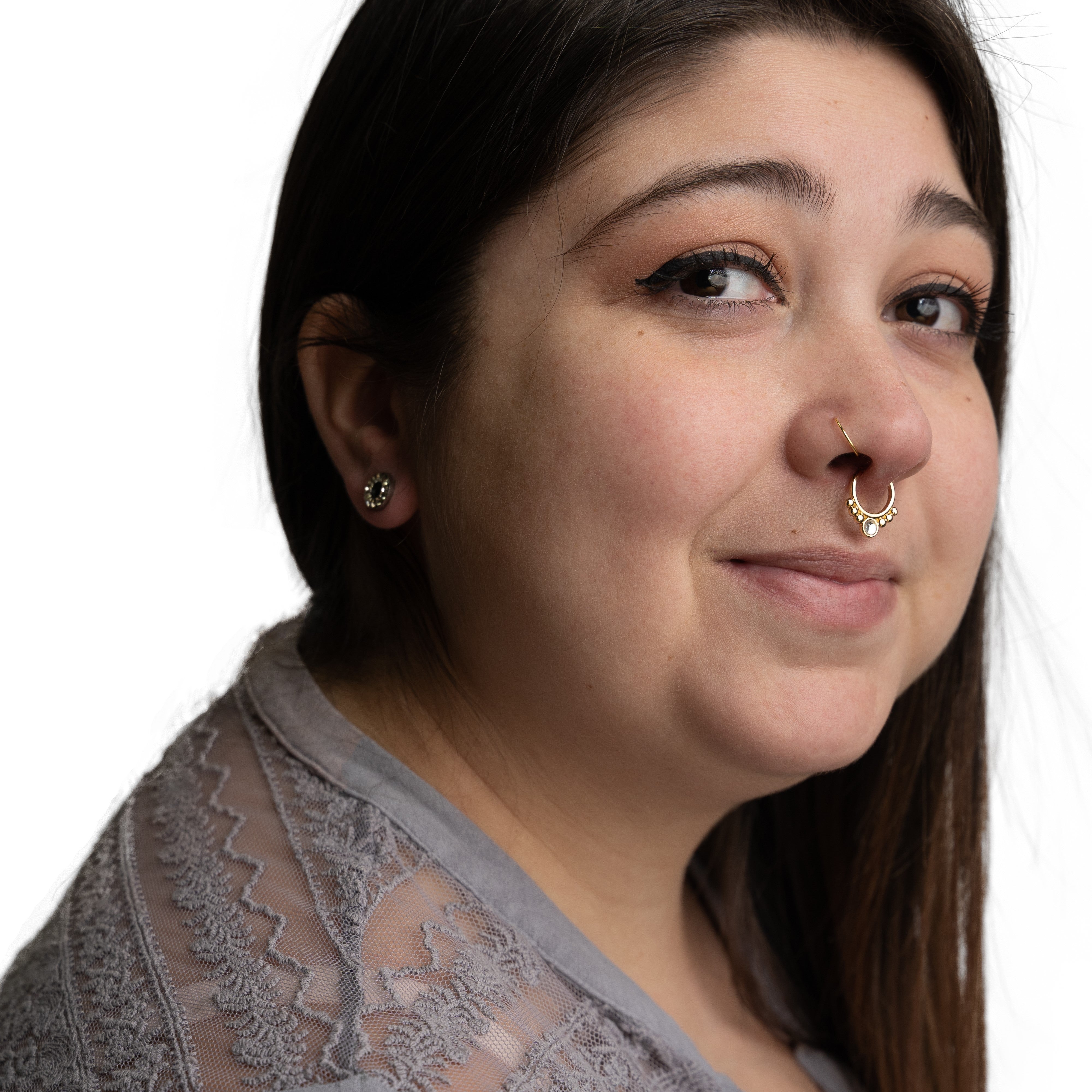 Portrait of a person featuring a decorative gold septum clicker and matching gold nostril hoop.