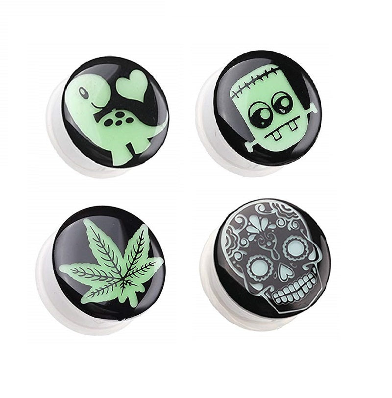 A set of acrylic glow in the dark tunnel plugs with various designs including frankenstein, sugar skull, mayan calendar, and dinosaur.