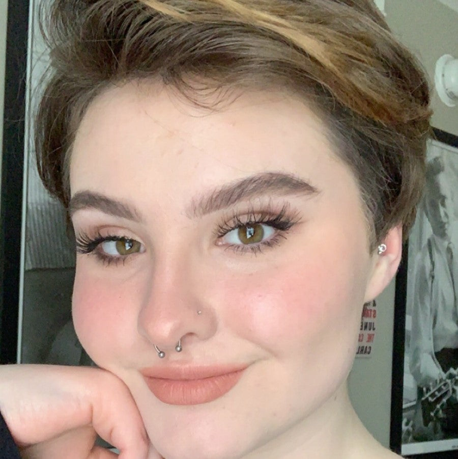 Close-up portrait of a person featuring a silver septum ring and nostril piercing.