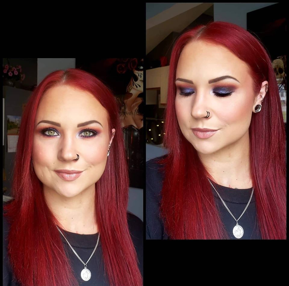 A person with vibrant red hair featuring a black double nose hoop, silver ear plugs, and multiple small silver cartilage piercings.